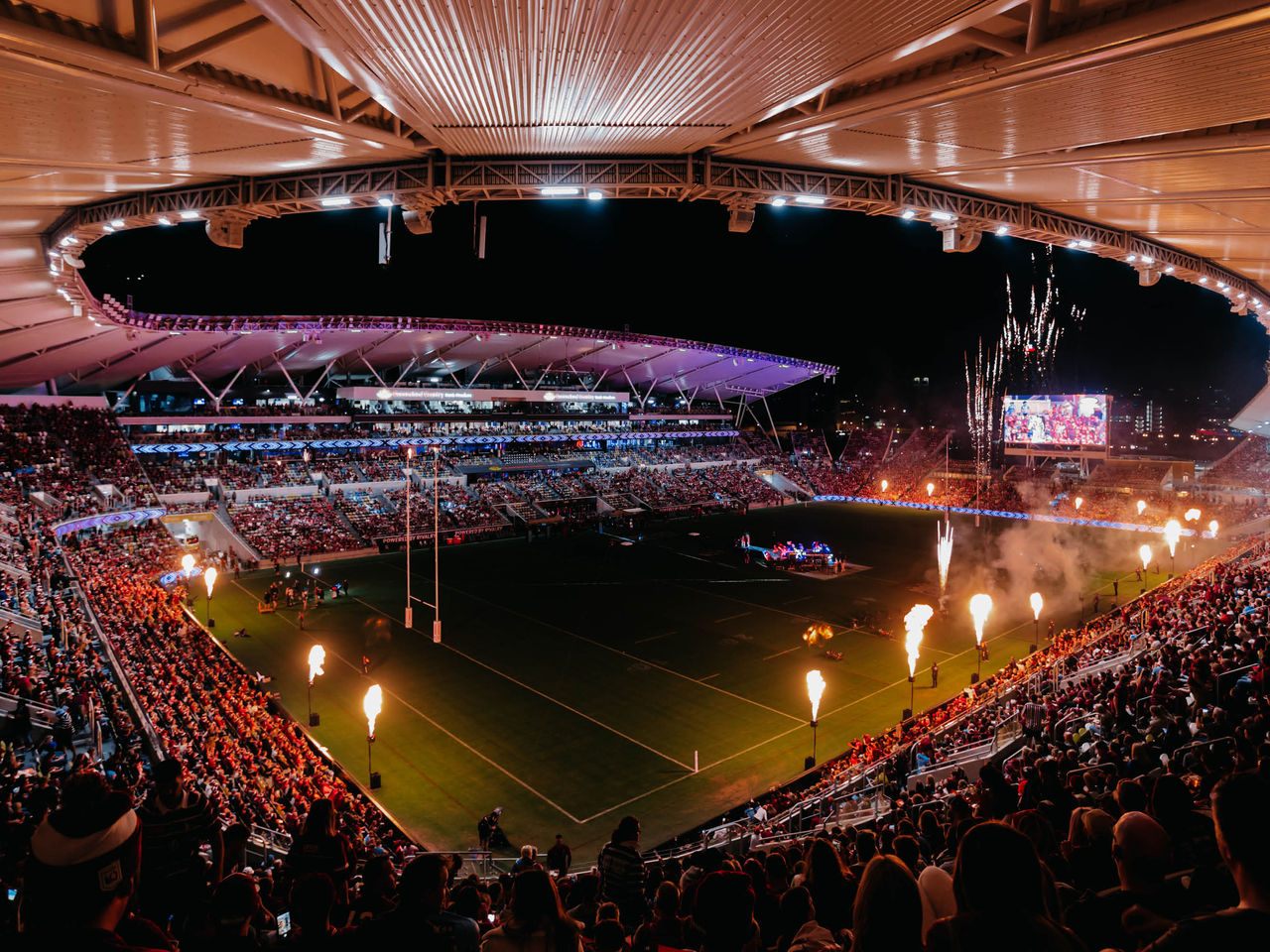 Queensland Country Bank Stadium lit up at night during a major event with pyrotechnics and a packed crowd